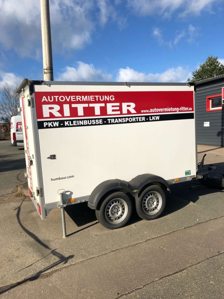 Weißer Kofferanhänger der Autovermietung Ritter mit Firmenbeschriftung.