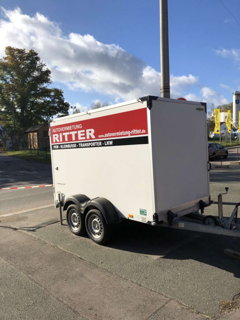 Weißer Kofferanhänger der Autovermietung Ritter in schräger Heckansicht.