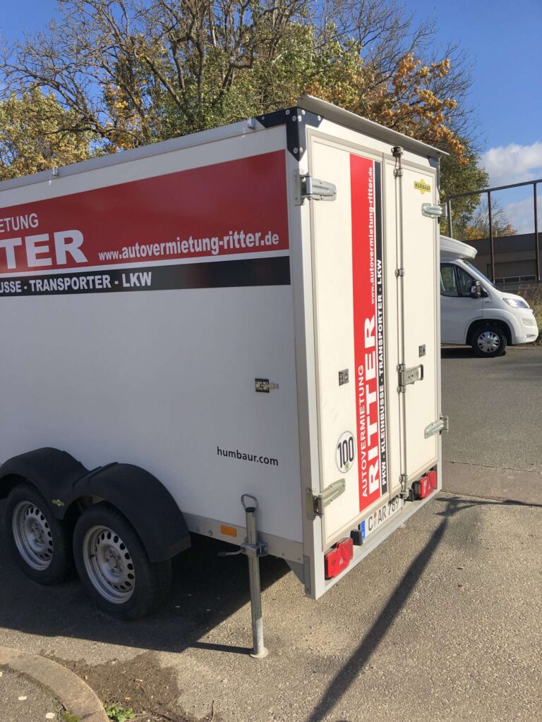Weißer Kofferanhänger der Autovermietung Ritter in schräger Heckansicht.