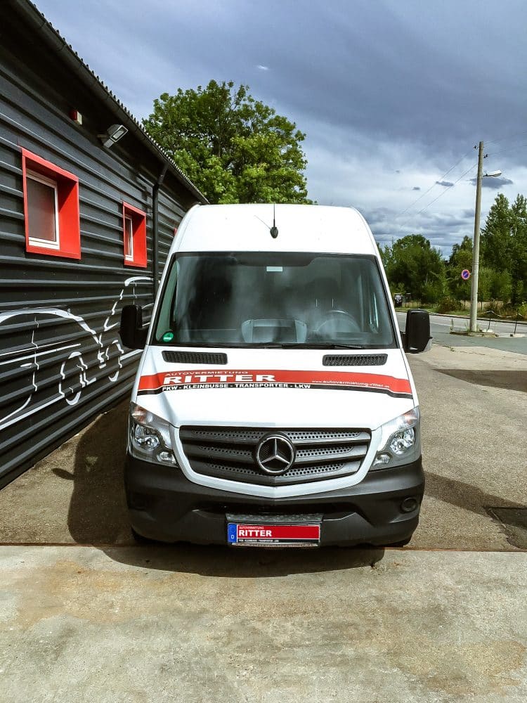 Weißer Mercedes Sprinter Transporter der Autovermietung Ritter vor einem Firmengebäude.