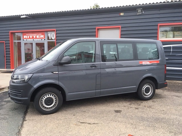 Grauer VW T6 Kleinbus der Autovermietung Ritter vor einem Firmengebäude.