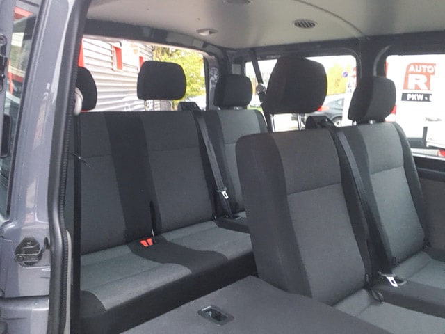 Innenraum eines VW T6 Kleinbusses mit mehreren Sitzreihen und Sicherheitsgurten.