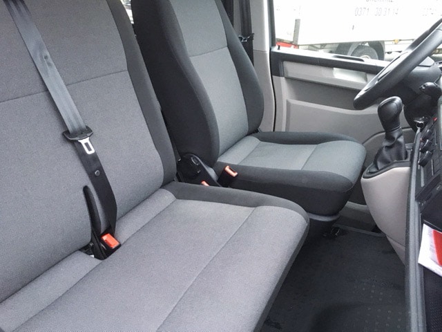 Sitzbereich eines VW T6 Kleinbusses mit grauen Sitzen und Sicherheitsgurten.
