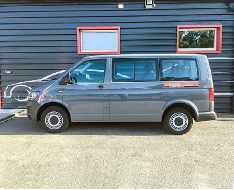 Grauer VW T6 Kleinbus der Autovermietung Ritter vor einem Firmengebäude.