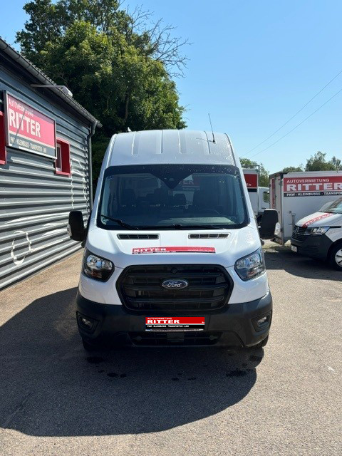 Weißer Ford Transit Kleinbus mit langem Radstand vor dem Gebäude der Autovermietung Ritter.