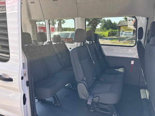 Innenraum eines Kleinbusses mit langem Radstand, mehreren Sitzreihen und Sicherheitsgurten.