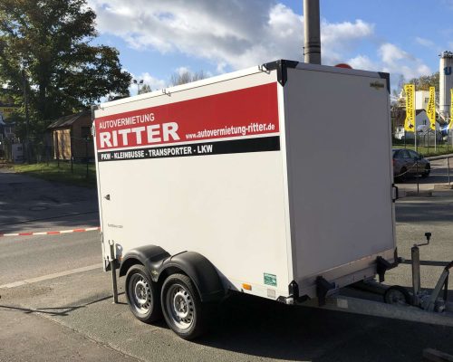 Weißer Kofferanhänger der Autovermietung Ritter in schräger Heckansicht.