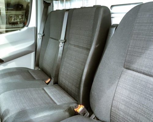 Sitzreihe im Mercedes Transporter mit Sicherheitsgurten und Stoffpolstern.