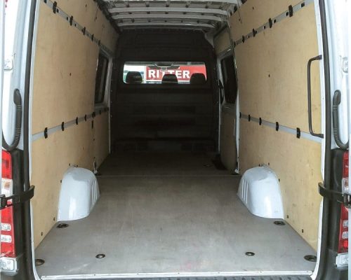 Innenraum eines Mercedes Sprinter mit leerer Ladefläche und Holzverkleidung.