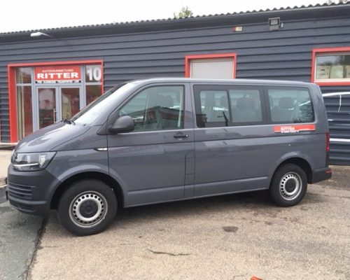 Grauer VW T6 Kleinbus der Autovermietung Ritter vor einem Firmengebäude.