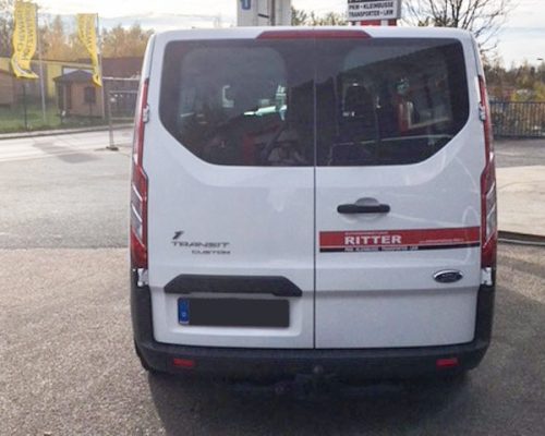 Heckansicht eines weißen Ford Transit Kleinbusses der Autovermietung Ritter.
